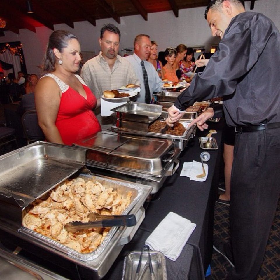 Guests at BBQ House Bar & Grill buffet line, serving themselves from chafing dishes.